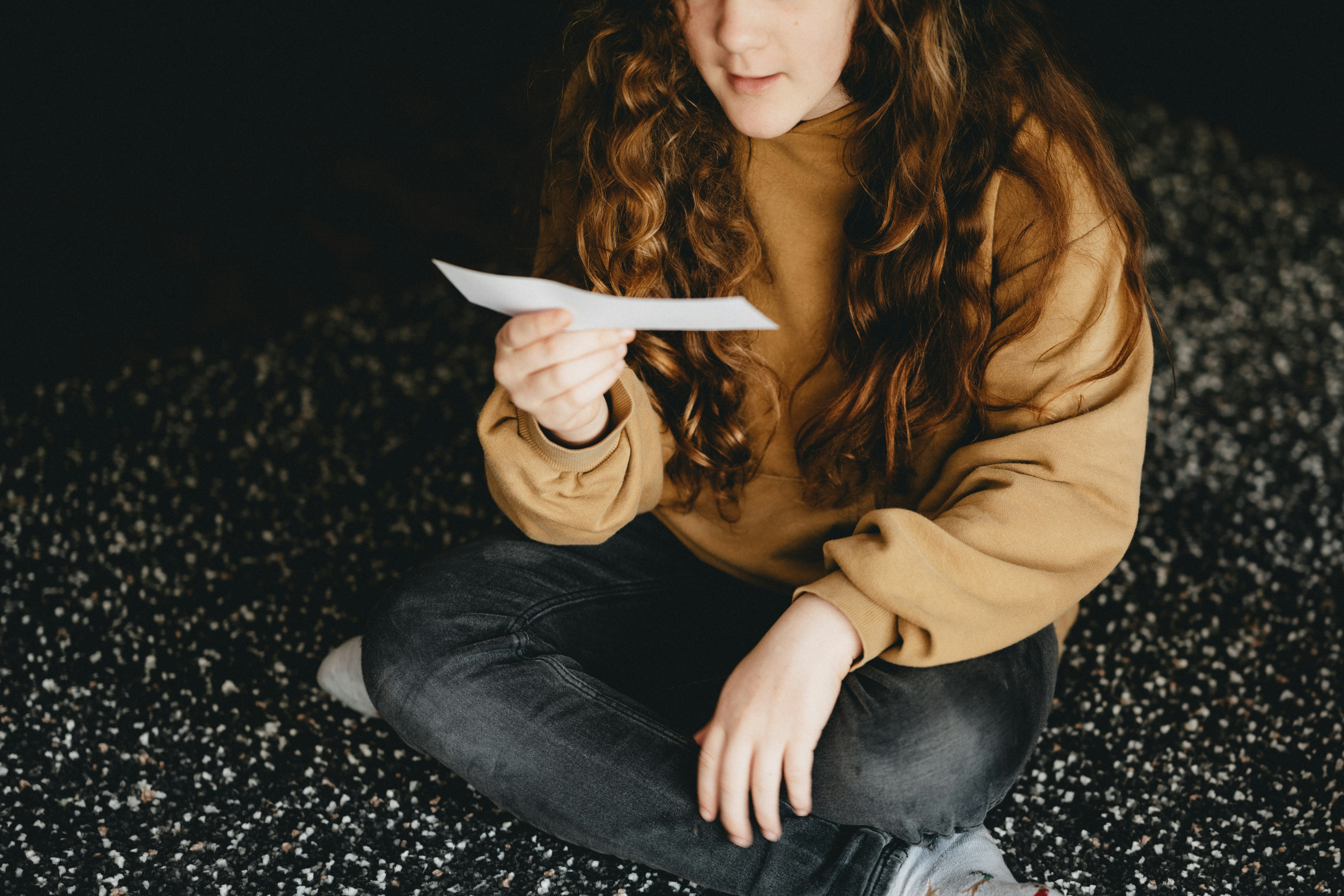 woman in brown long sleeve shirt and blue denim jeans sitting on black and white textile